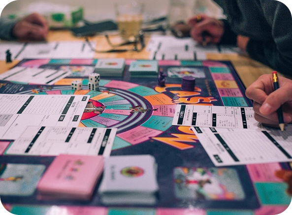 Mensen spelen een bordspel met dobbelstenen en kaarten.